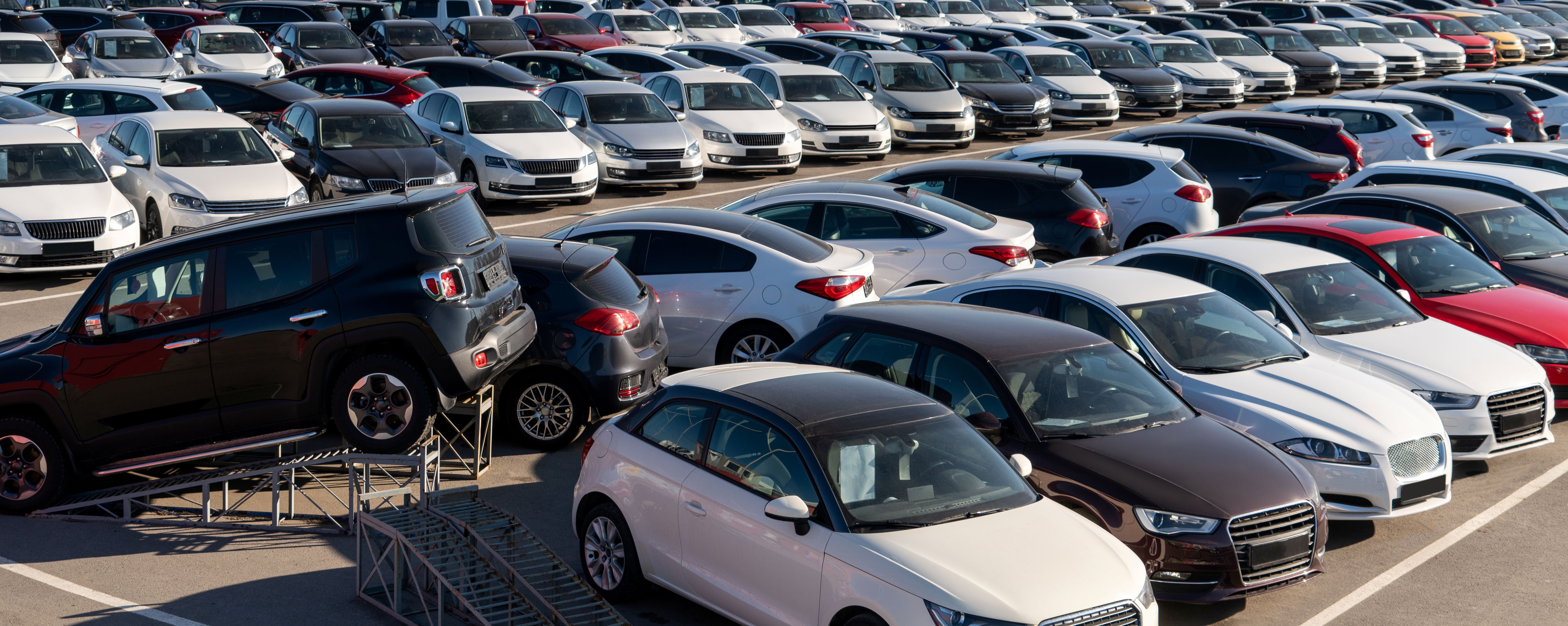 Rows of used sedans, hatchbacks, and SUVs for sale at a car dealership